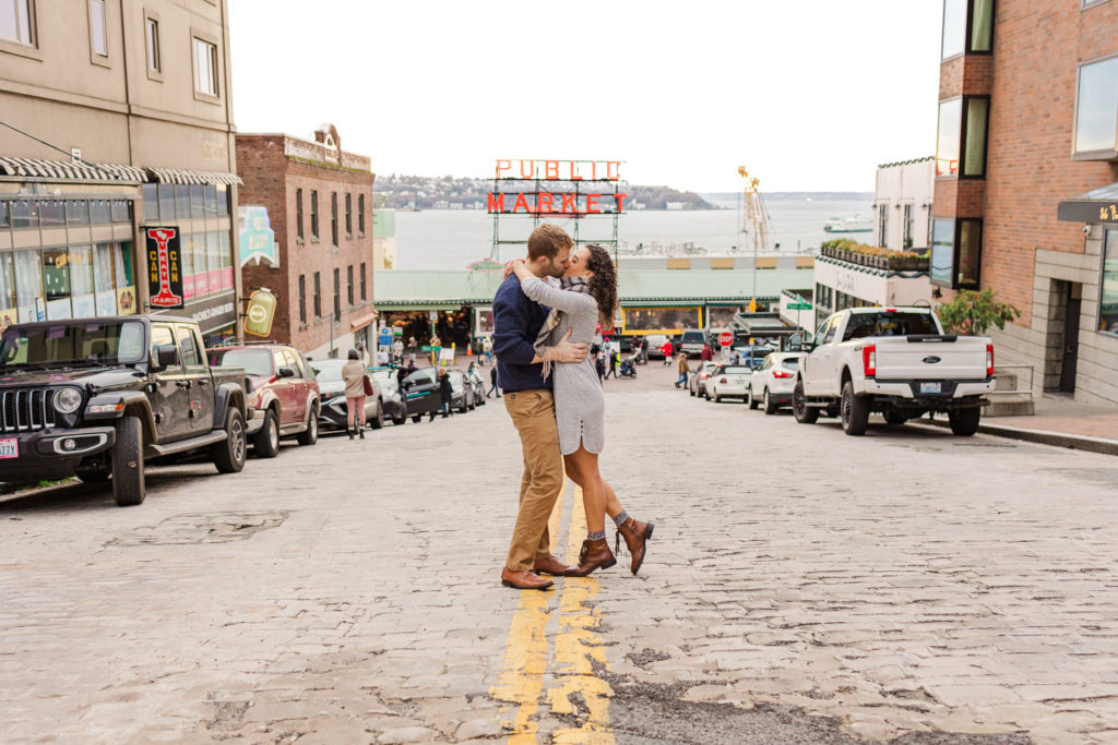 Man and woman kissing in front of Pike Place Market in Seattle WA