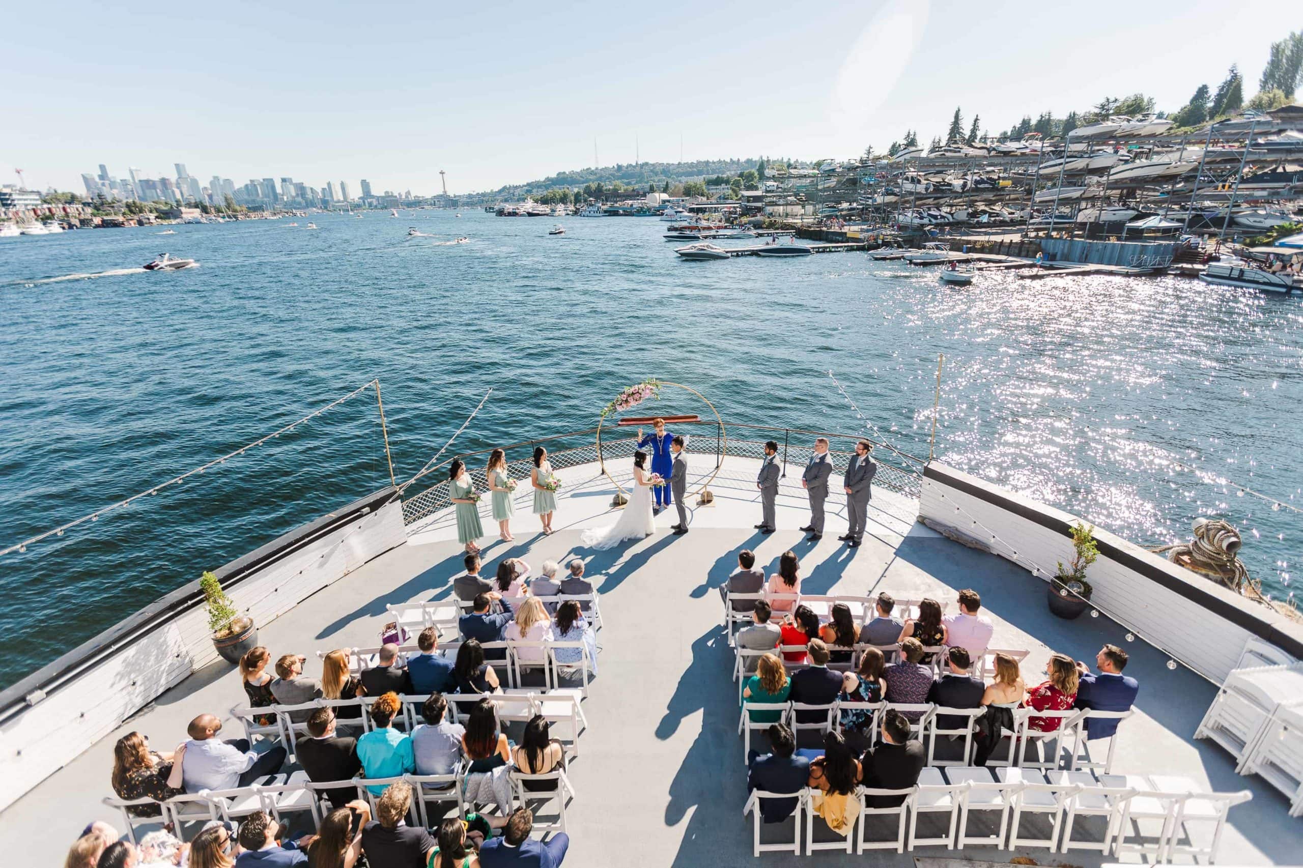 Looking down at a wedding ceremony on the balcony of a boat. You can see the Seattle skyline in the background.